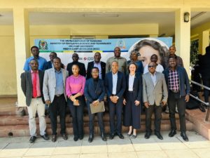 Groupphoto: Some of the attendees of the presentation held by Prof Hornidge stand together with her in front of a banner for a formal photo.