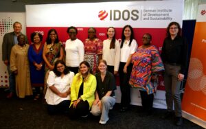 Photo: Participants of the Workshop "Local feminist perspectives as transformation levers for greater gender equality" in Bonn, standing in front of a Wall with many IDOS-Logos, Bonn, 23.10.2024