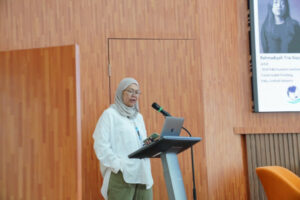 Irina Rafliana on the stage, speaking into a microphone