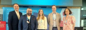 Groupphoto: Five people pose in front of a poster for the Global Media Forum, including IDOS researchers Dr Semuhi Sinanoğlu and Dr Anita Breuer.