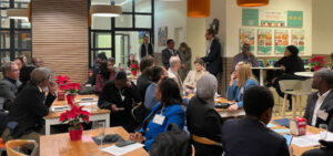 Photo: Several tables where participants in the peer learning workshop sit together.