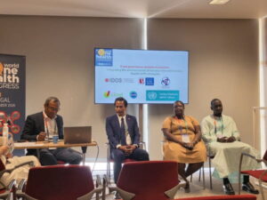 Podiumsdiskussion auf dem 9. World One Health Congress in Lissabon. Vier Teilnehmende sitzen vor einer Präsentationsfolie zur Verankerung der Umweltdimension in nationalen Strategien gegen antimikrobielle Resistenzen (AMR).