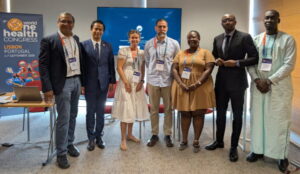 Gruppenfoto von Teilnehmenden der Science-Policy-Session beim 9. World One Health Congress in Lissabon. Die Gruppe steht vor dem Veranstaltungsbanner und einer Präsentationsfläche nach einer Diskussion zu Governance-Ansätzen für die Bekämpfung antimikrobieller Resistenzen.